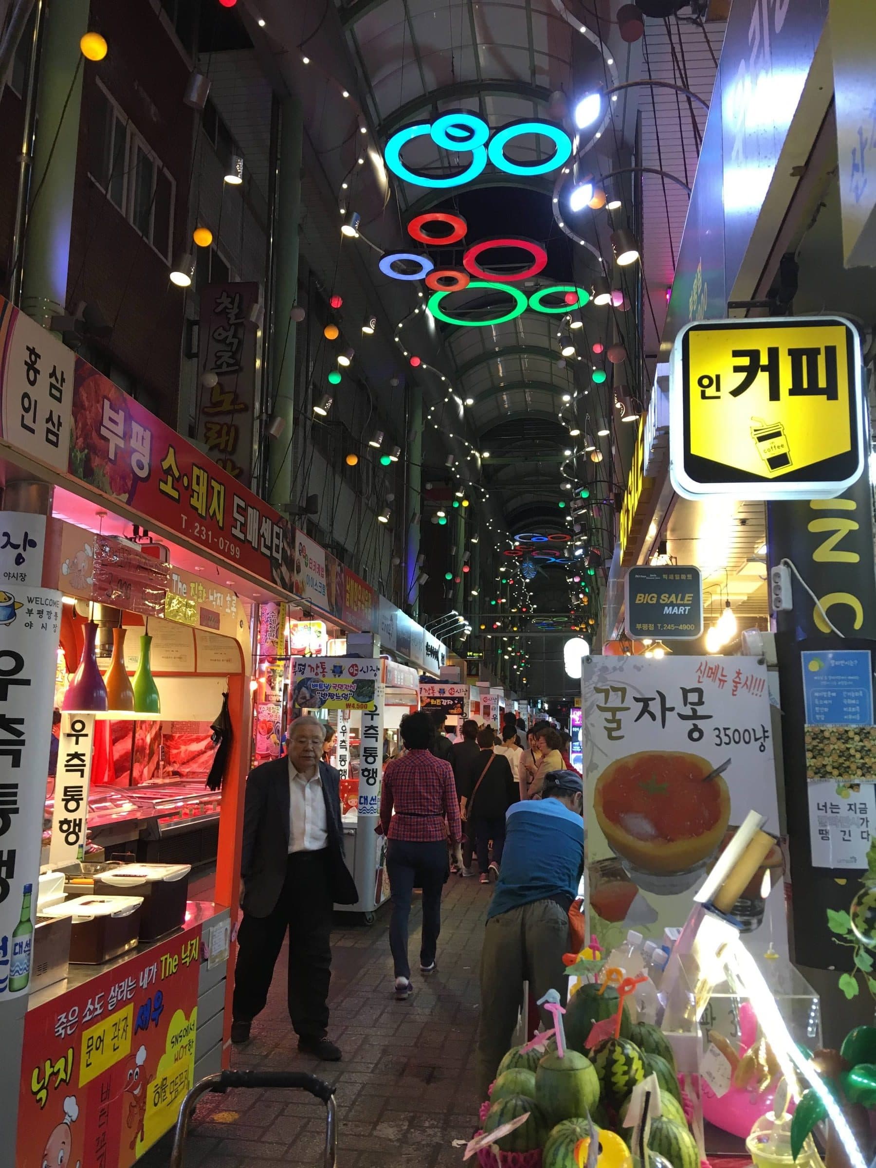 Lit food and drink stalls along a covered alley at the Bupyeong Kkangtong night market in Busan