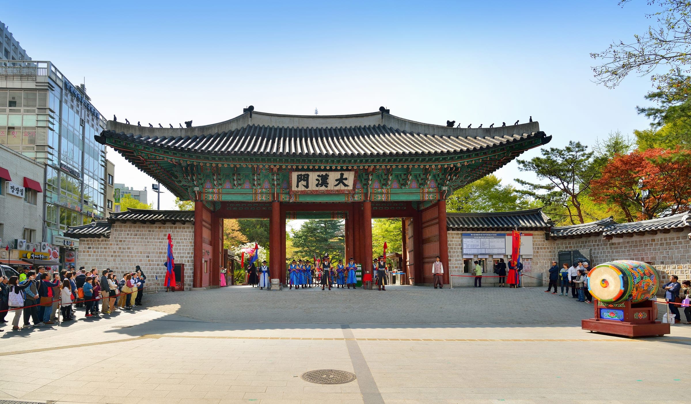 Daehanmun, the main gate of Deoksugung Palace in central Seoul, with gate guards in the forecourt and visitors watching