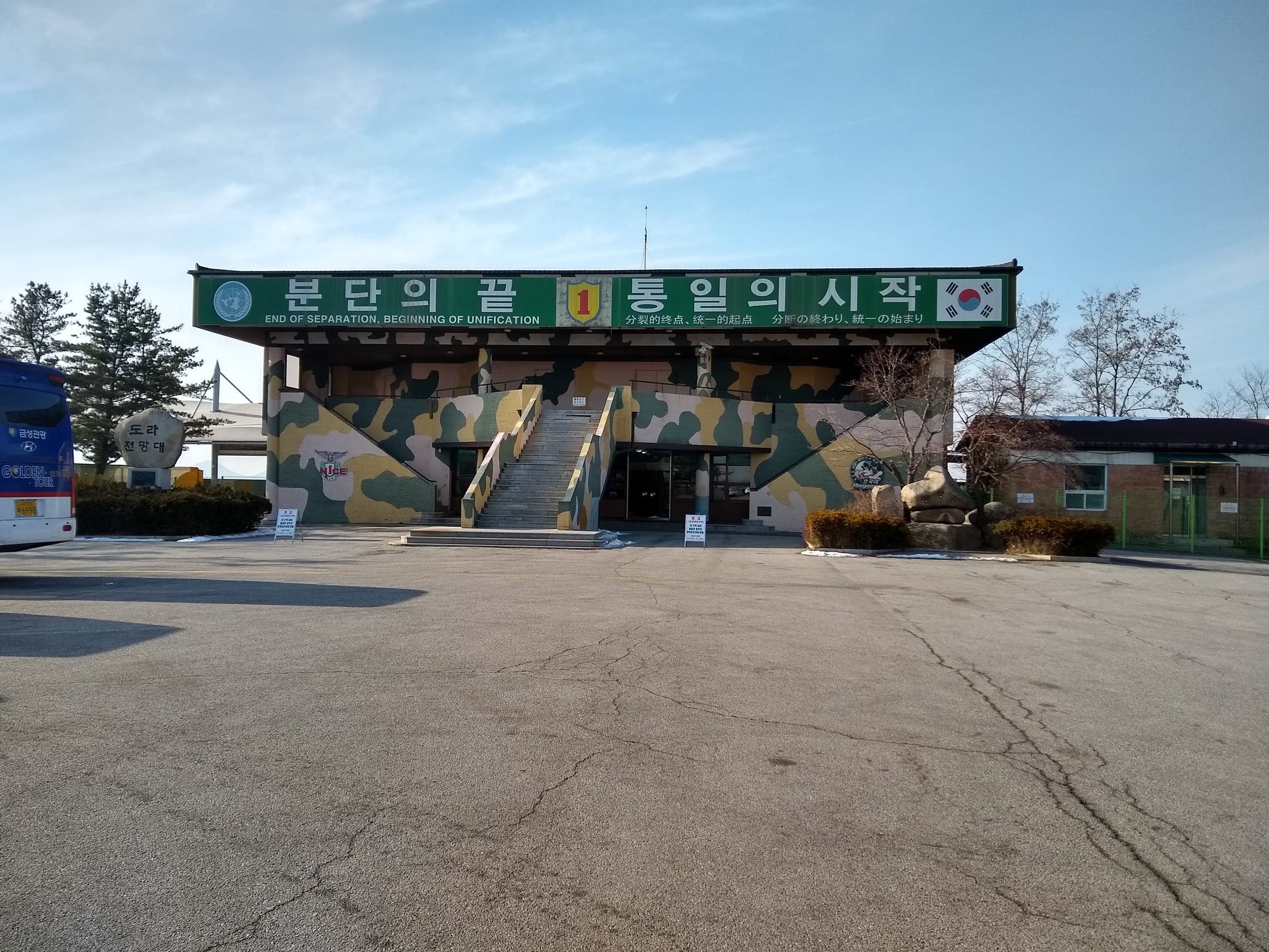 The camouflage-painted Dora Observatory building under a green sign on a clear day