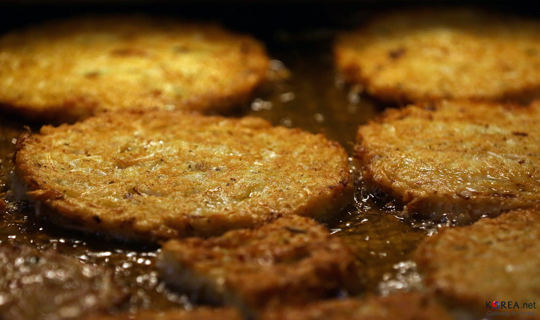 Close-up of mung bean pancakes frying in oil at Gwangjang Market in Seoul