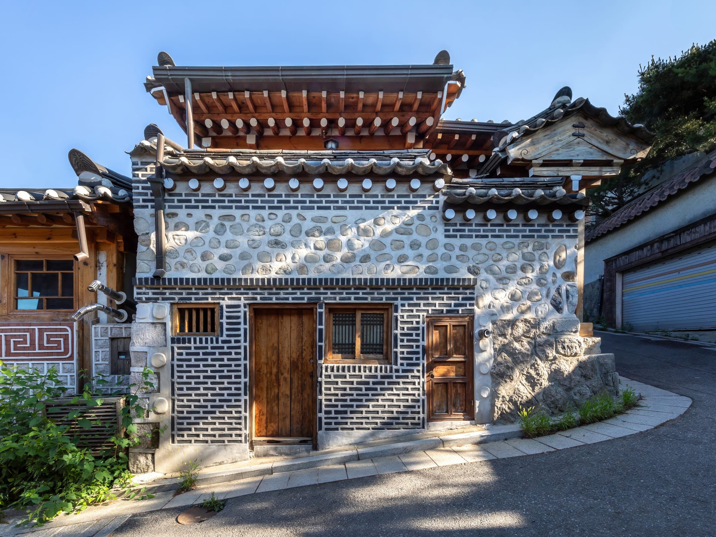 A hanok house with closed wooden doors on a steep residential lane in Bukchon Hanok Village