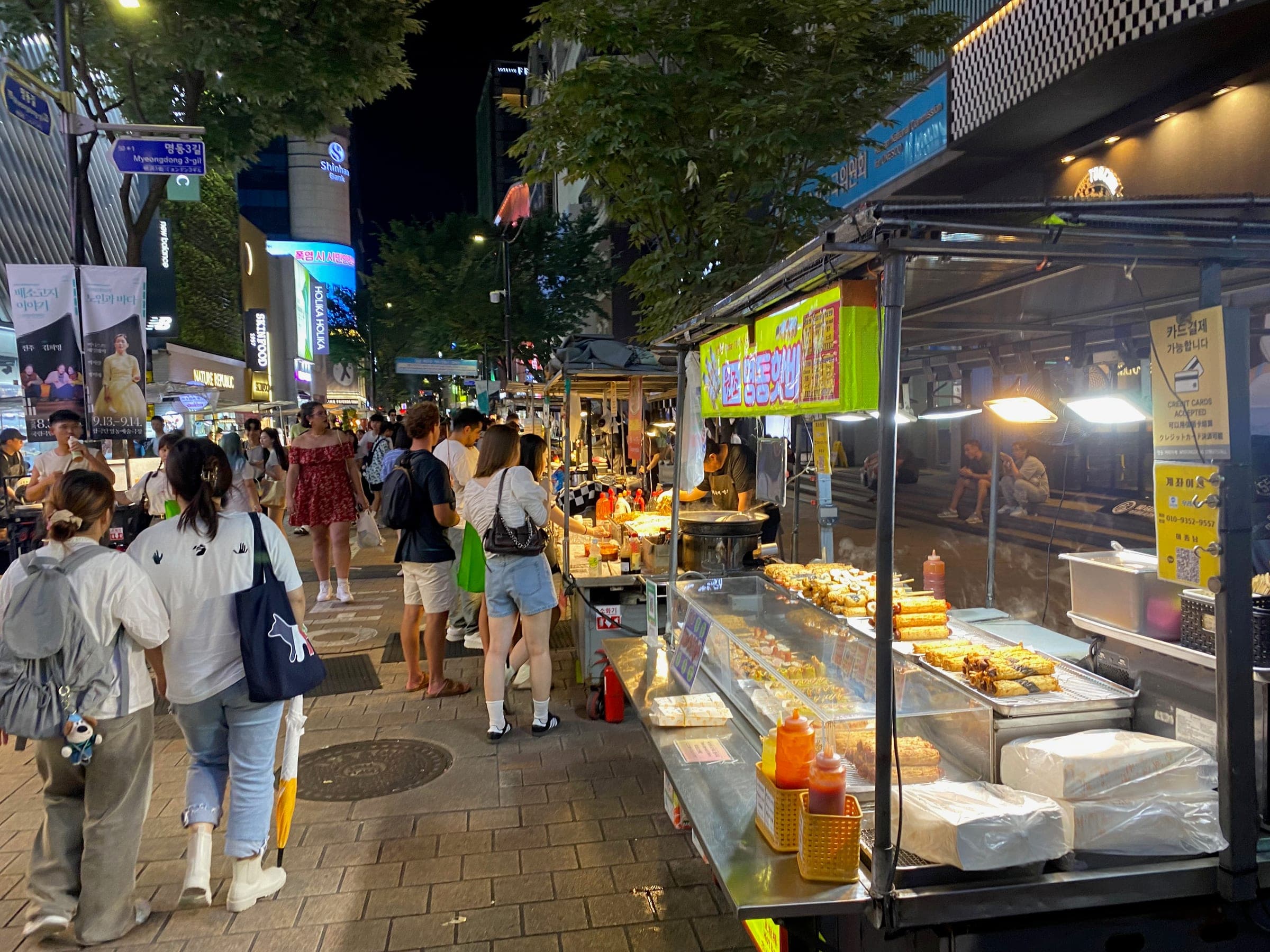 Street food stalls and shoppers on a Myeongdong street at night