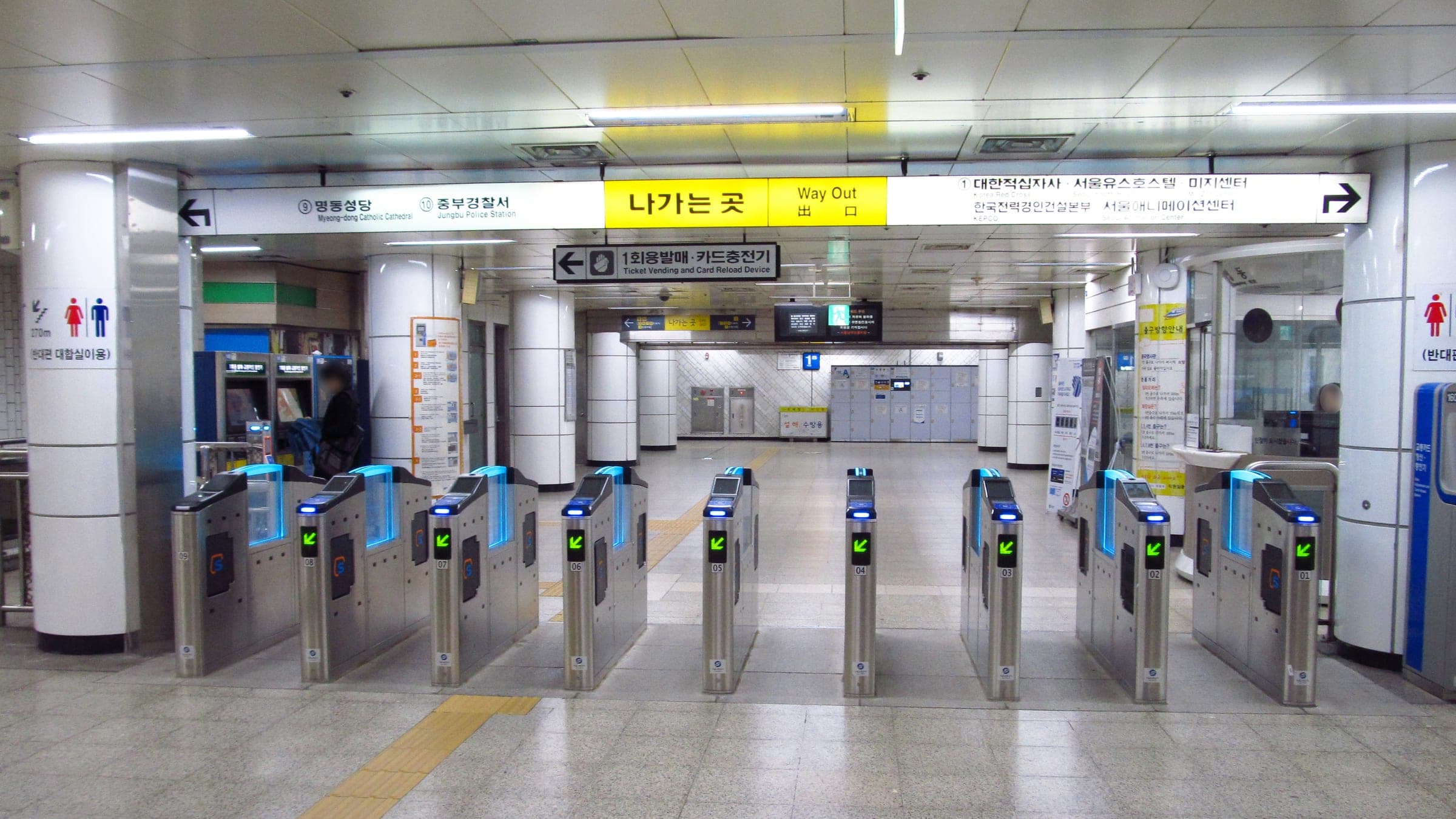A row of card-tap ticket gates under a Way Out sign at Myeongdong subway station