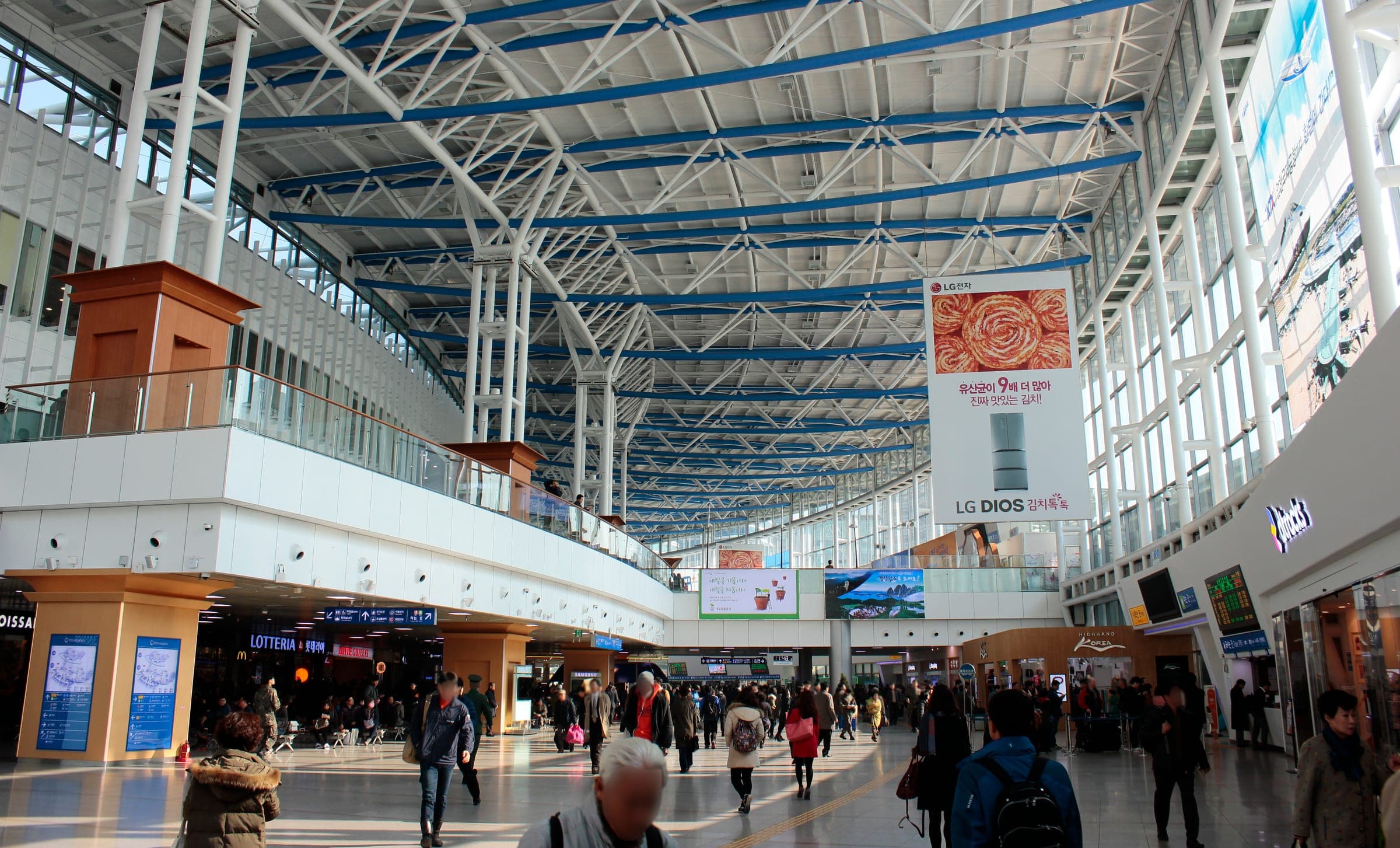 Travellers crossing the high glass-roofed concourse of Seoul Station
