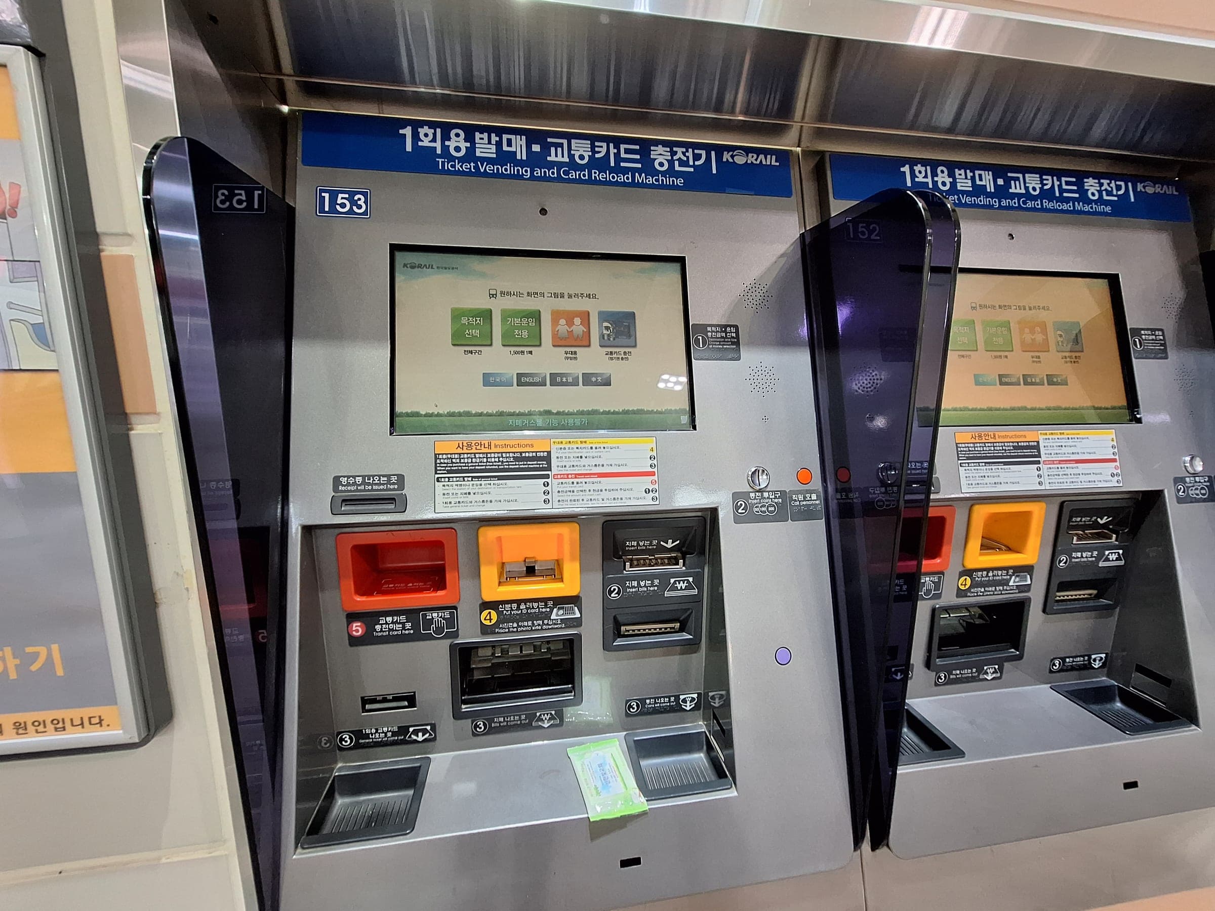 Two ticket vending and transit card reload machines with touchscreens and cash slots in a Seoul subway station